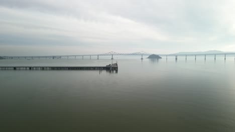 drone aligns wooden pier with richmond bridge from point molate beach richmond california usa