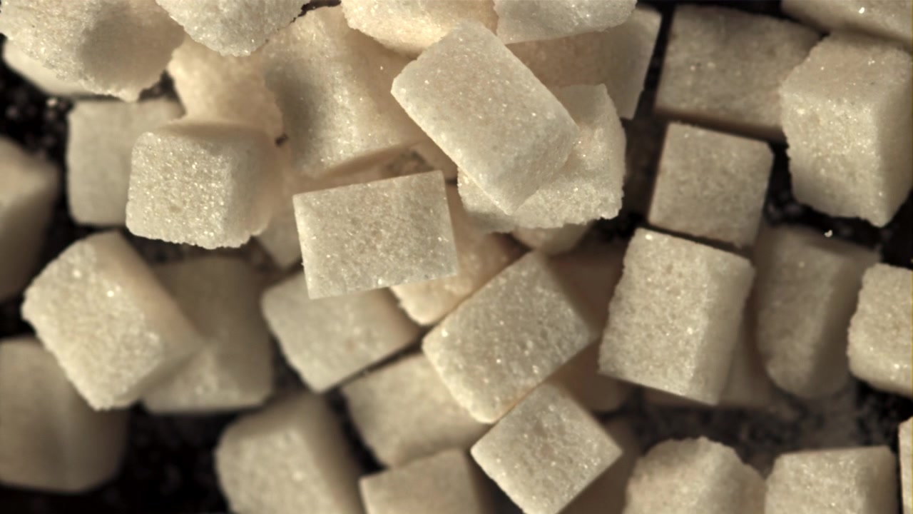 Foto macro de cubos de açúcar focando em uma superfície escura