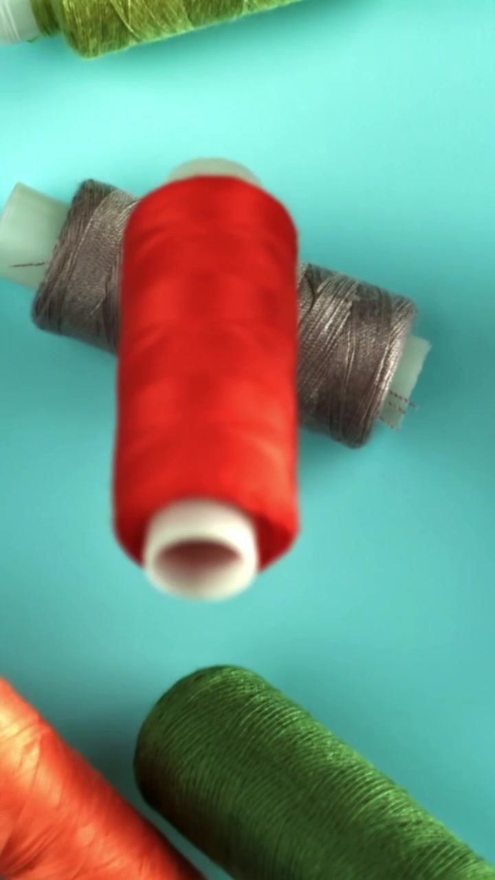 Colorful Spools of Sewing Thread Coming into Focus on Blue Background