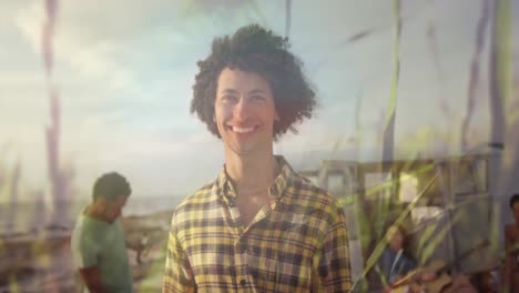 animation of smiling mixed race man with friends at beach over grass