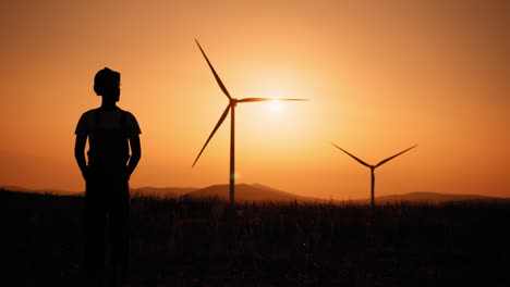 person at sunset with wind turbines