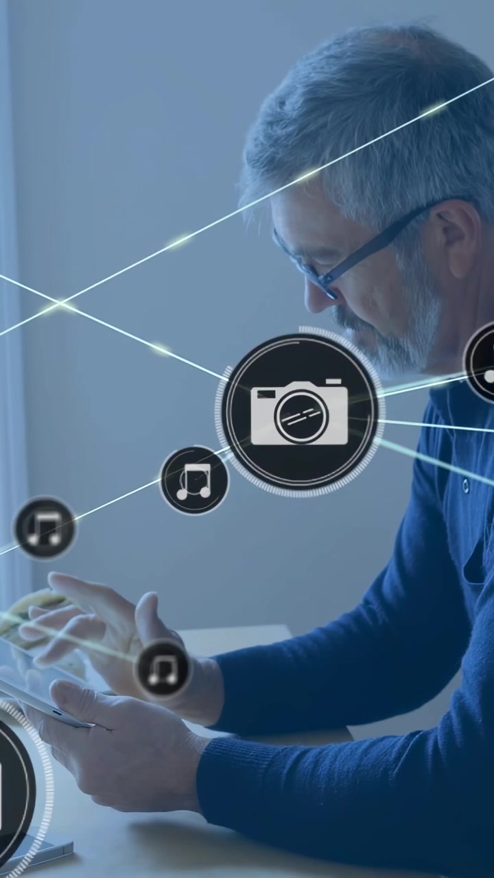 Vertical video: Man tapping tablet sparking camera and music icons over man and table to sort media