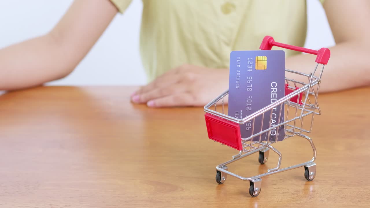 A shopper makes a credit card payment using a tiny cart symbolizing modern retail transactions