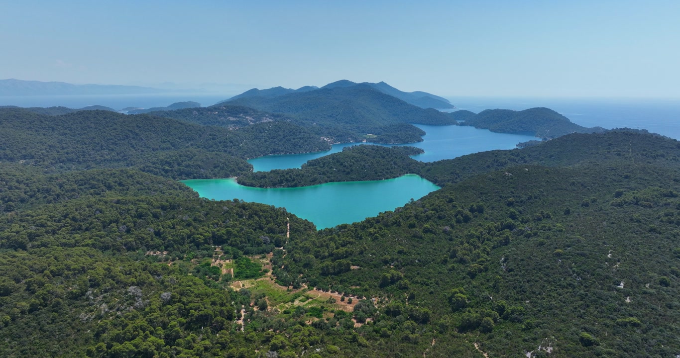 Panoramic aerial shot of forested mountains and turquoise lakes in Mljet National Park, Croatia