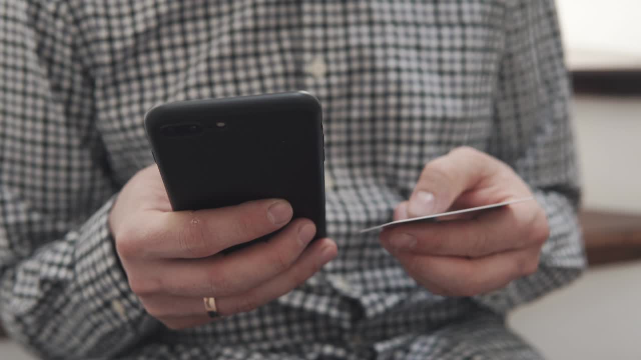 남자가 스마트폰과 신용카드를 손에 들고 타이핑하고, 클로즈업