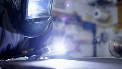 Close-shot-of-a-worker-welding-with-a-blowtorch-and-a-face-shield