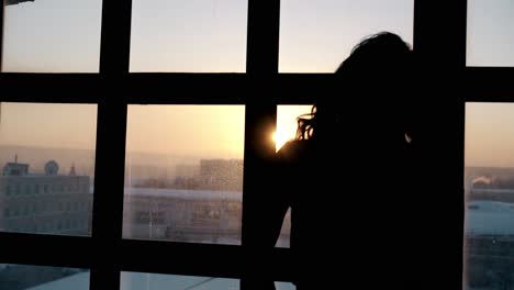 Silueta-De-Mujer-Mirando-Por-La-Ventana-En-La-Ciudad-De-Invierno