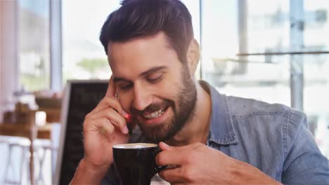 man talking on mobile phone while having coffee