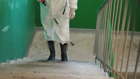 a man in protective uniform spraying the steps of the house with an antiseptic