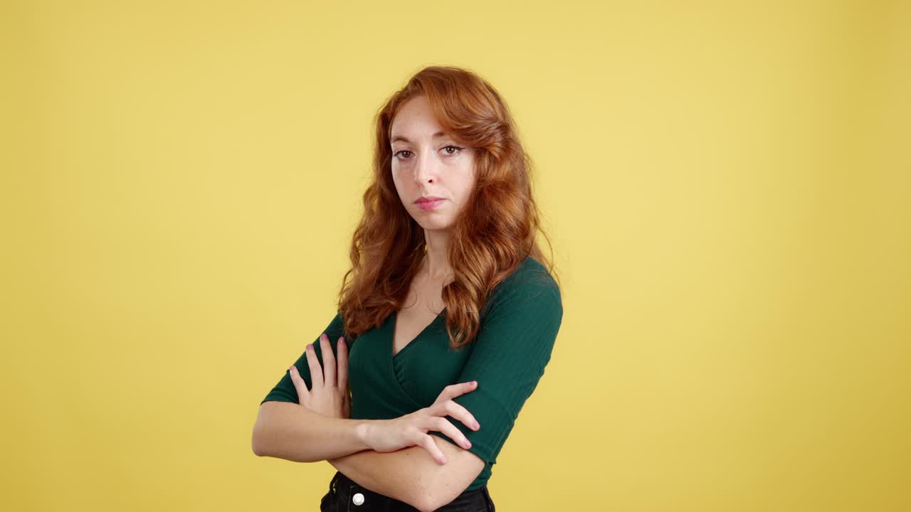Young Woman with Red Hair and Crossed Arms on Yellow Background