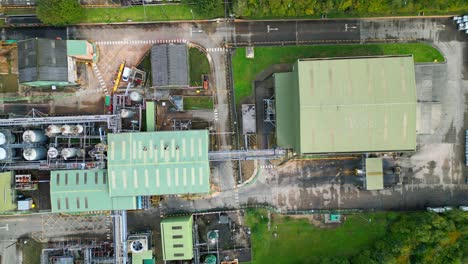 aerial view progresses toward a british chemical plant, displaying pipelines, metal frameworks, cooling towers, and chemical storage