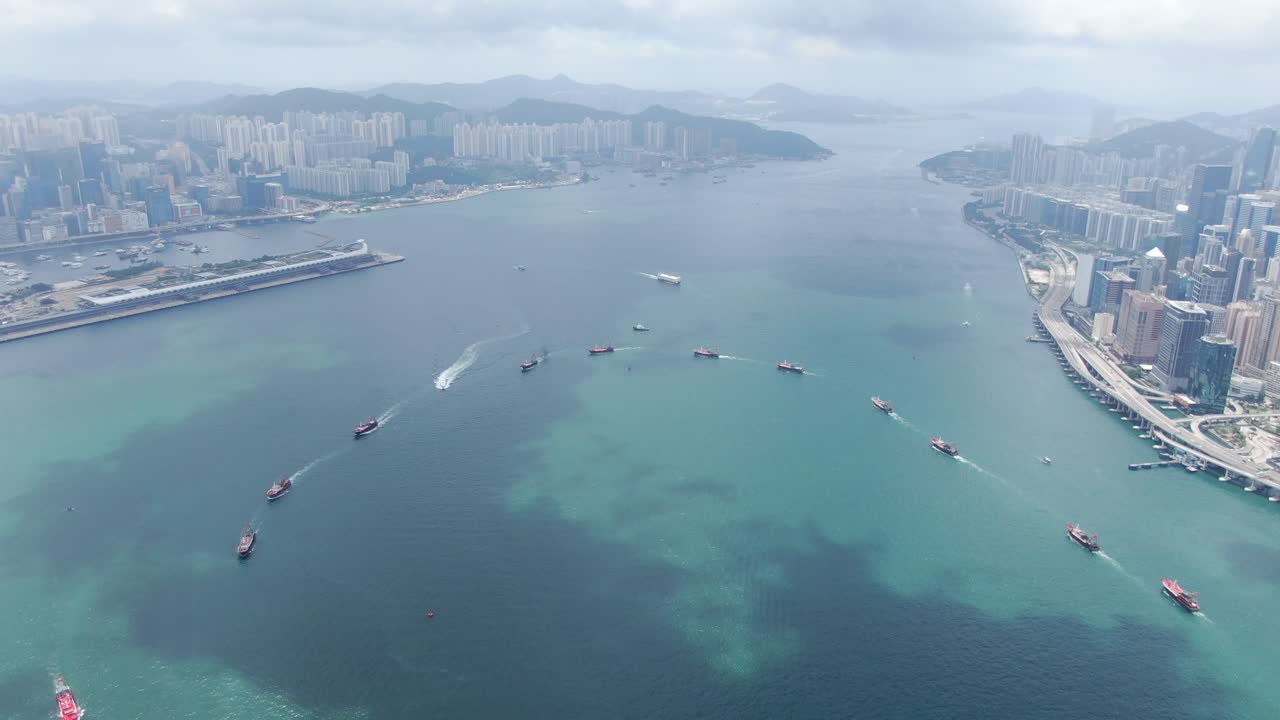 convoy de barcos de pesca locales que causan en la bahía victoria de hong kong, con el horizonte de la ciudad en el horizonte, vista aérea