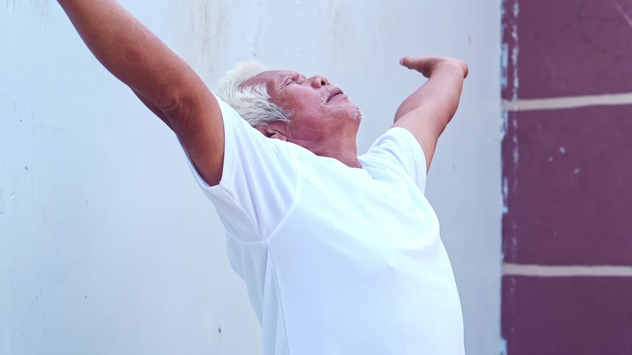 Elderly asian man Breathing Exercises feeling refreshed and energized outdoors in daylight
