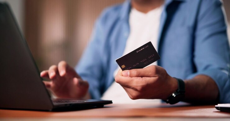 Man Shopping Online Using Credit Card and Laptop