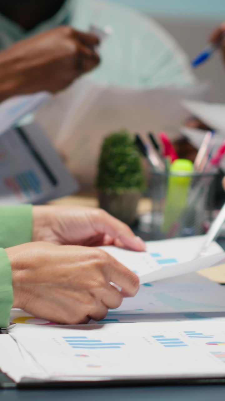 Vertical Video Close up of diverse specialists evaluating data numbers on archived files