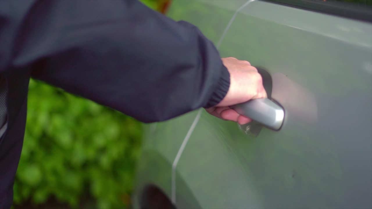 두건을 쓴 남자가 차 문을 훔쳐 차나 무인 안에 남겨진 귀중품을 훔치려 한다