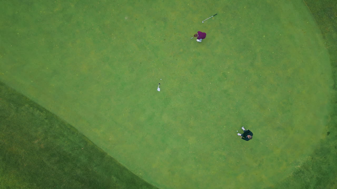 Two golfers playing green lush field summer day top view. Calm players focusing