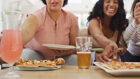 Felices-Y-Diversas-Amigas-Sentadas-En-El-Sofá-De-La-Sala-De-Estar,-Comiendo-Pizza