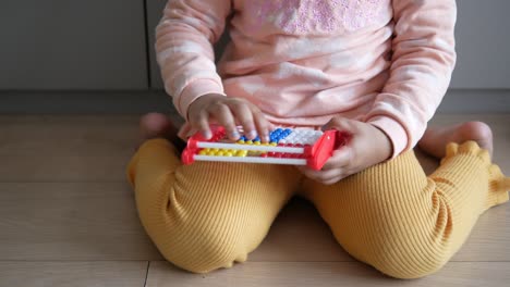 niña pequeña jugando con un colorido juguete de ábaco