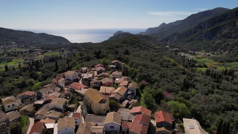 droneshot delantero sobre aldea aislada en la cima de una montaña verde en grecia