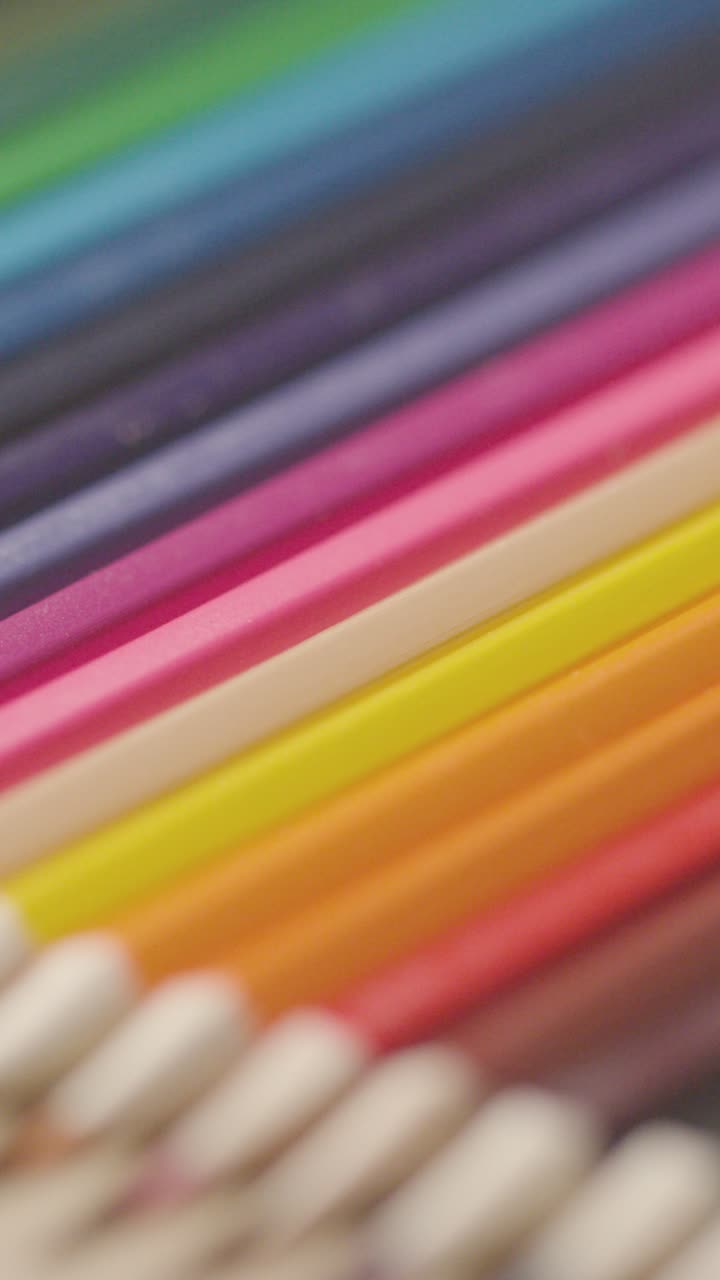 vídeo vertical de lápices de colores dispuestos en una línea sobre un fondo de madera 1