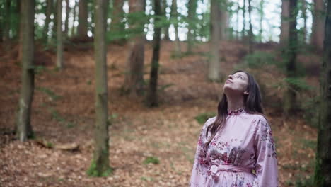 young girl in long sleeves floral dress stop and looking up on trees