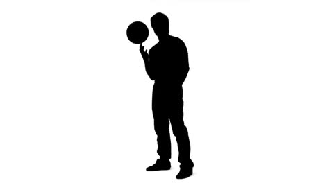 silhouette of a man balancing a ball on his finger in slow motion