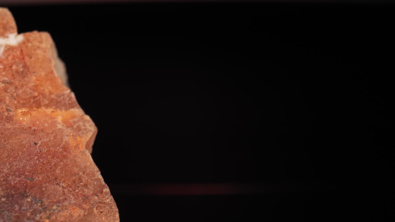 Cinematic pan of a studio-lit citrine quartz cortex crust against a dark background