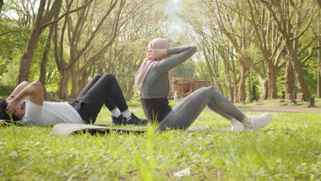 couple doing sit-ups in a park