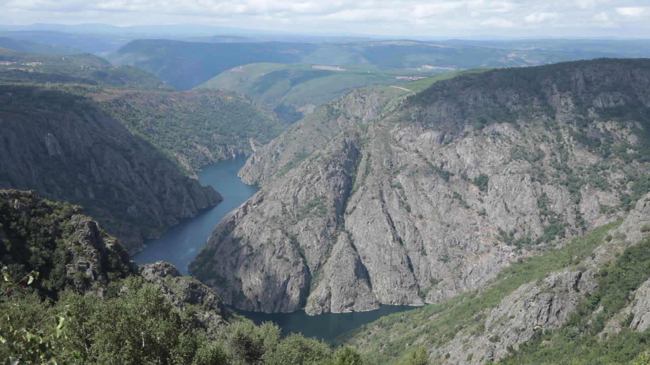 Scenic view of a deep gorge with cliffs and a river winding through lush green mountains