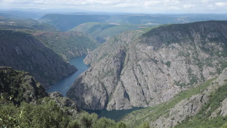 scenic view of a deep gorge with cliffs and a river winding through lush green mountains