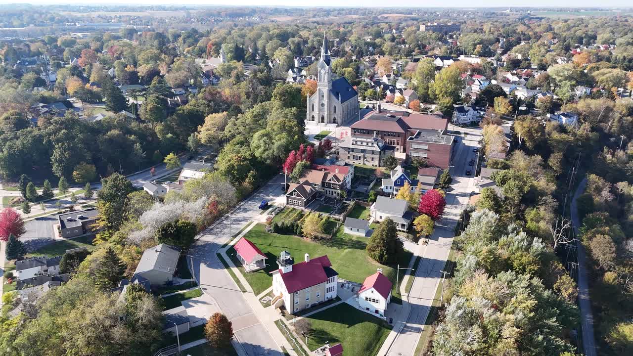 Slow cinematic aerial view of downtown Port Washington WI featuring iconic the beautiful Saint Mary's church sitting high atop the hillside