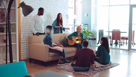 group of friends playing guitar in a large modern apartment