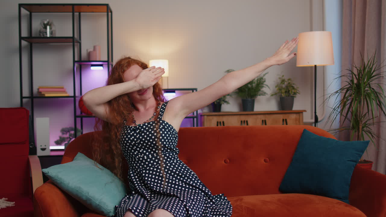 트렌디하고 즐겁고 긍정적 인 귀여운 소녀 춤추고, 리에 따라 움직여서 현대 가정에서 더브 댄스 제스처를 만니다.