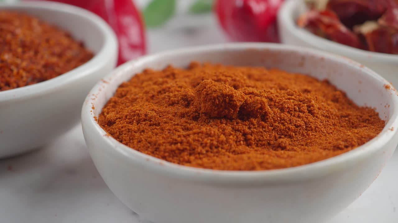 Close Up of Red Chili Powder and Flakes in White Bowls