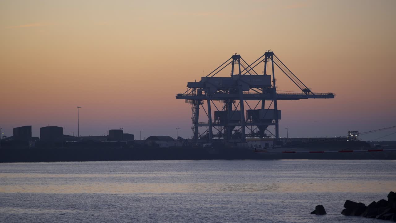 terminal portuario de contenedores de sines con grúas al atardecer, en portugal