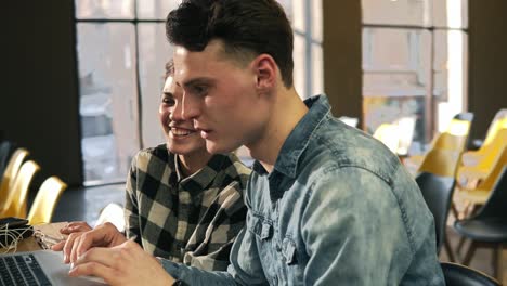 two attractive young people, guy and a girl in their 20's, spending time together, laughing and searching the web.