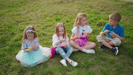 group of happy children outdoor. group of happy children sitting on green grass outdoors in park