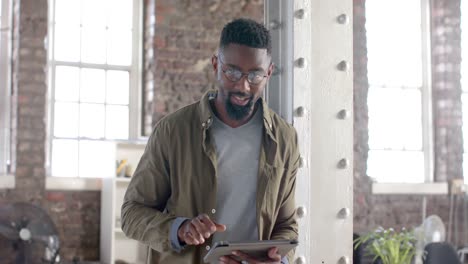 Portrait-of-happy-african-american-casual-businessman-using-tablet-in-slow-motion