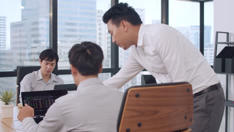 japanese male boss supervisor teaching intern or new employee chinese young guy helping with difficult assignment at meeting room.