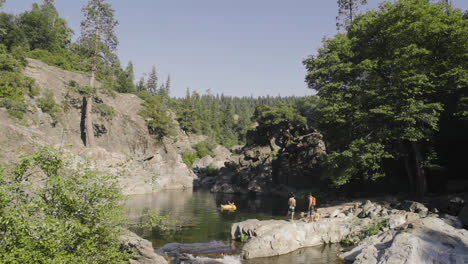 Group-of-friends-hanging-out-by-a-beautiful-clear-swimming-hole-in-the-Sierra-Nevada-mountains-near-Lake-Tahoe-California-in-slow-motion-4k-after-a-long-hike