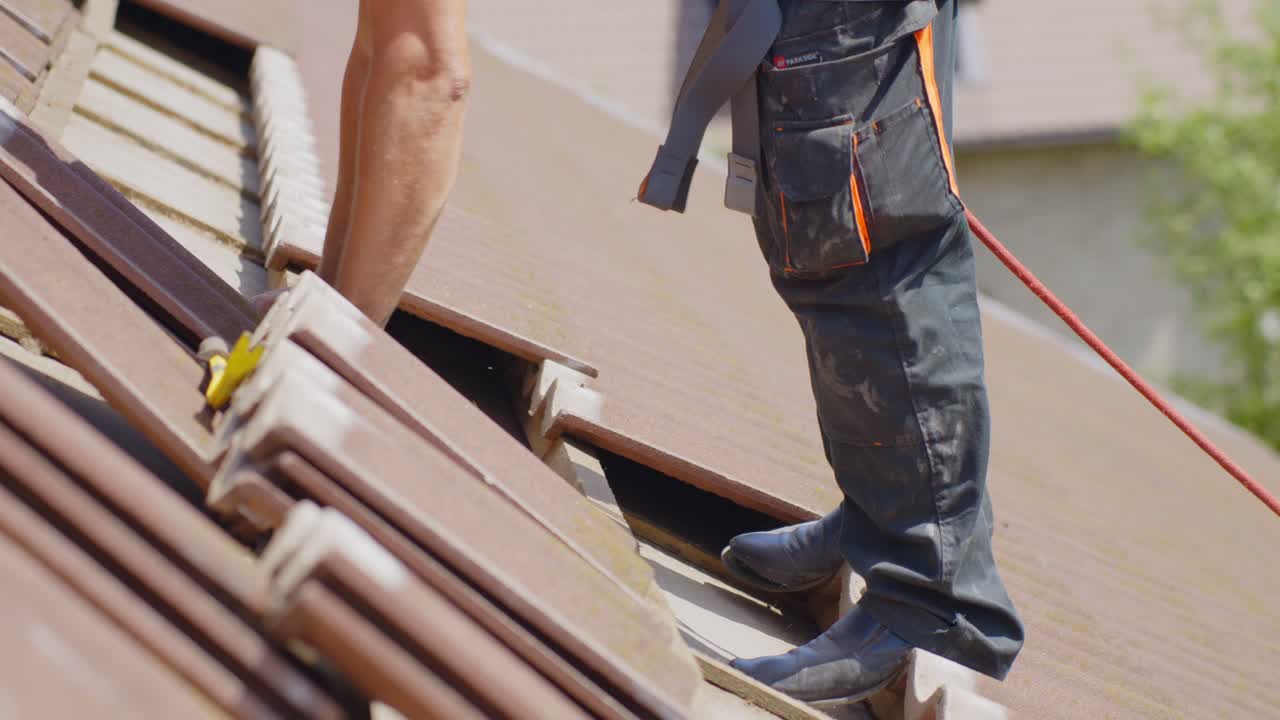 Roof preparation for solar panel installation, tile removal, worker with safety rope