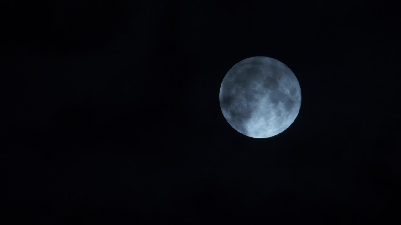 Nuvens passando pela lua cheia brilhante e iluminada no céu noturno escuro