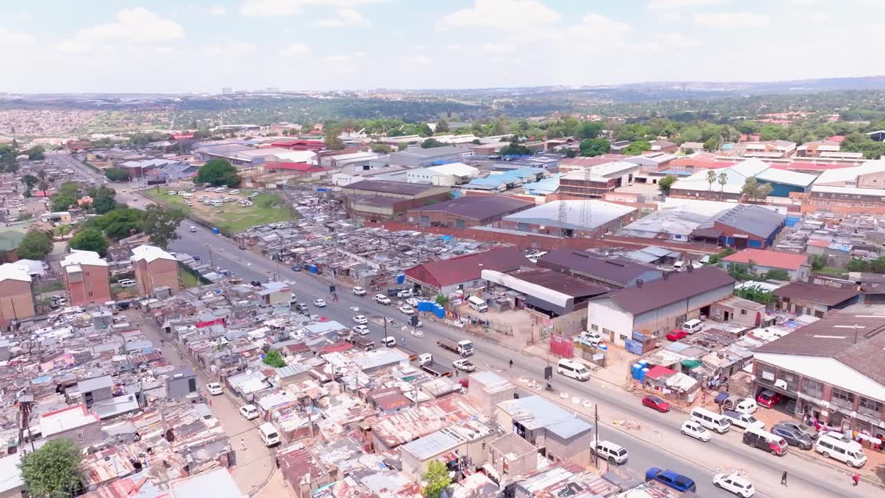Aerial panning shot over Alexandra Township, Johannesburg, South Africa, on a sunny day with scattered clouds and cars moving on main road