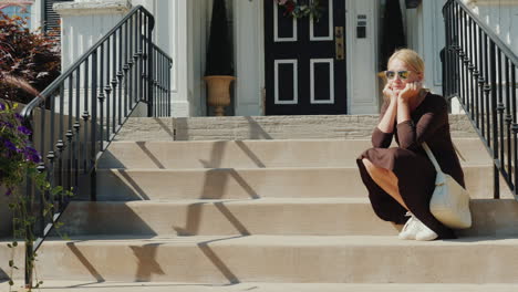 a woman sits on the steps on the porch of the house