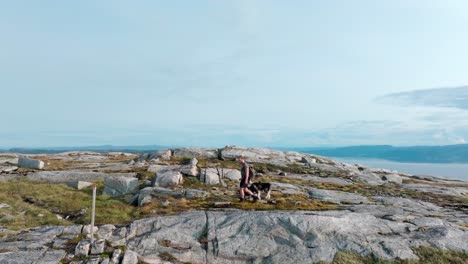 man and pet dog on a hike at mountain blaheia in nordland, norway