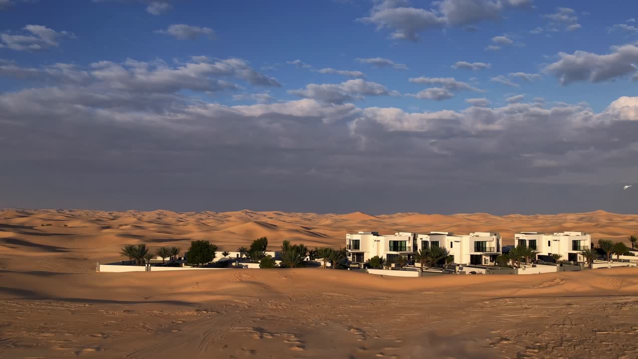 Pristine white architectural structures rising from golden sandy terrain, complemented by dramatic clouded sky highlighting architectural minimalism against natural landscape