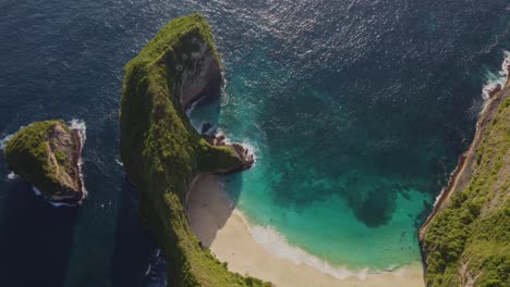 iconic aerial top-down view of kelingking beach, nusa penida, indonesia. dramatic cliffs, turquoise water, and a pristine hidden beach. stunning tropical landscape from above. shot in 4k.