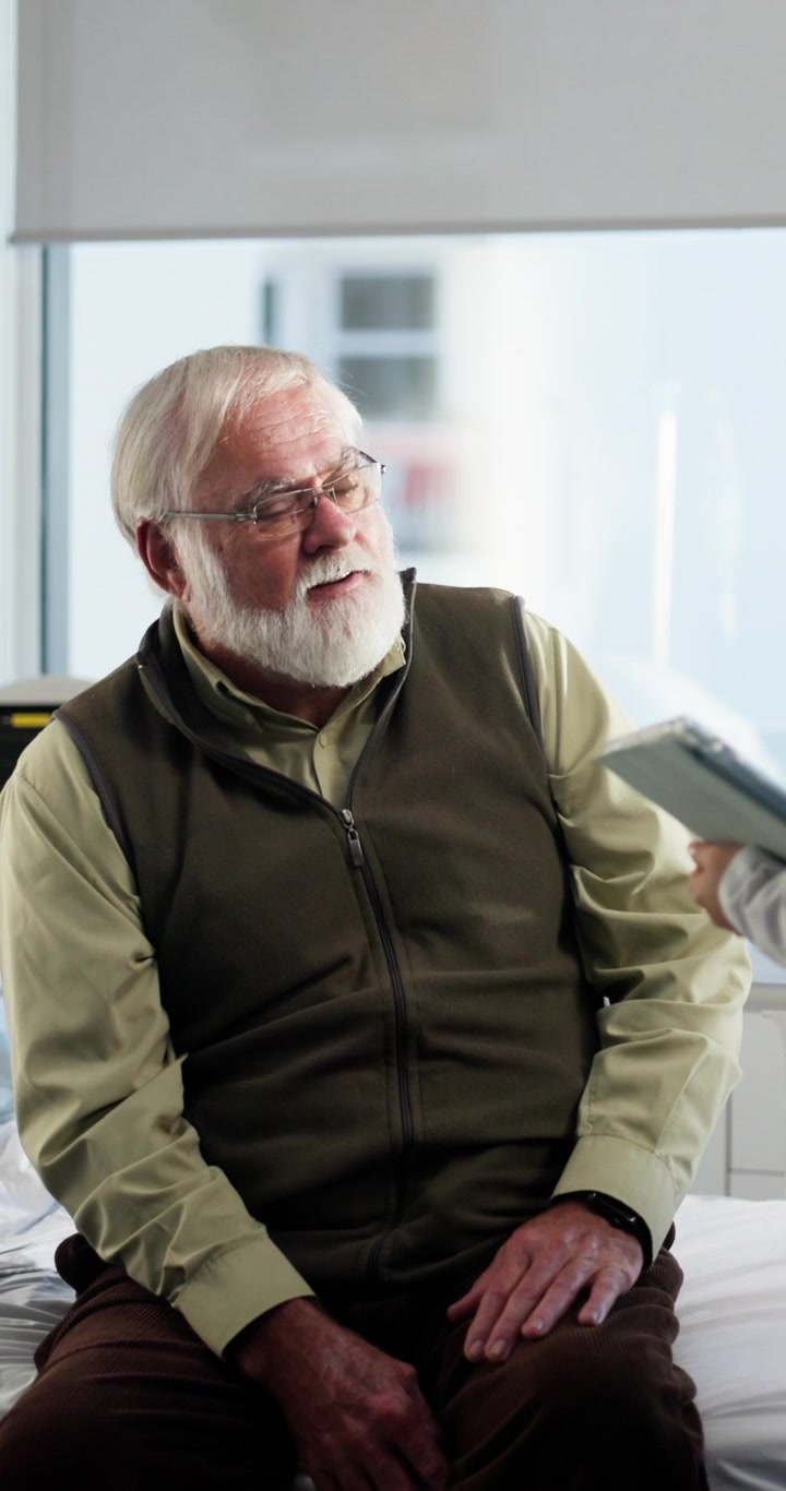 Senior Man Talking to Doctor in Hospital Room