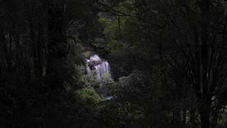 view of large waterfall from afar amongst rainforest greenery